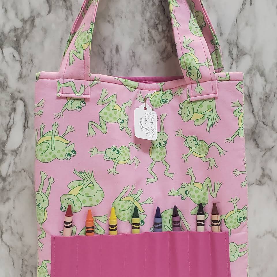 A pink tote bag with crayons on it